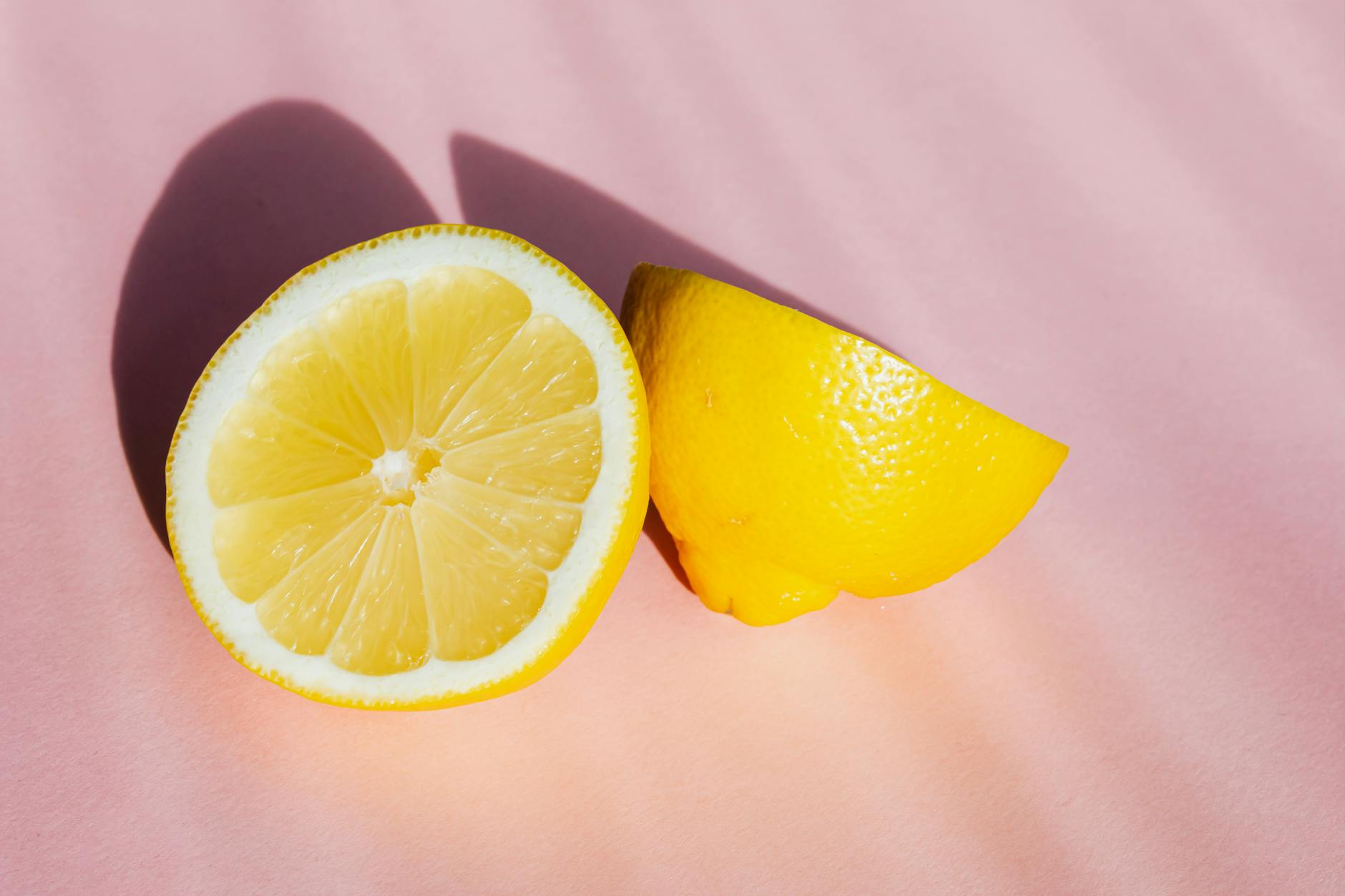 Fresh lemon halves on pink background in bright light