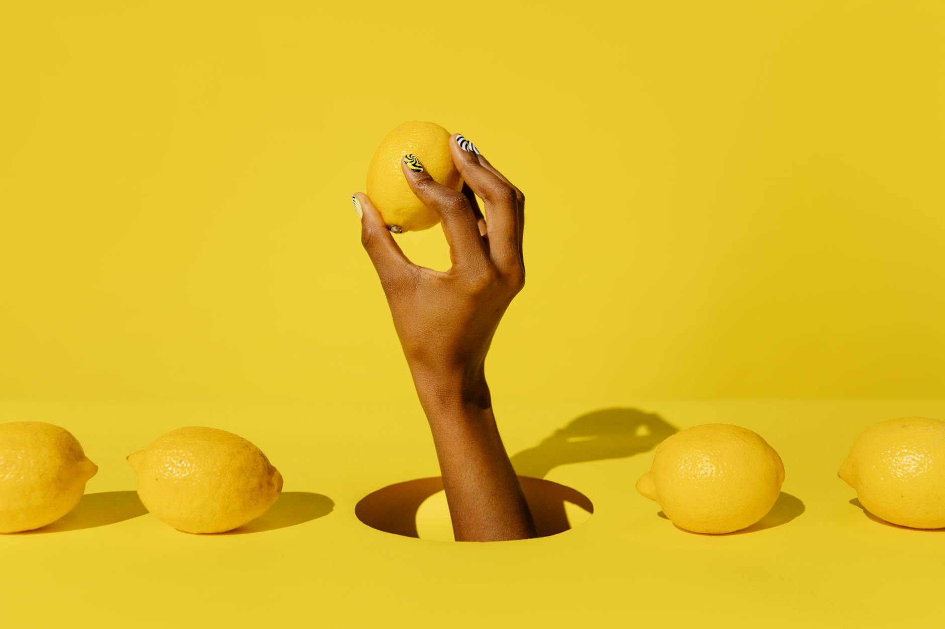 Woman holding fresh lemon on yellow background