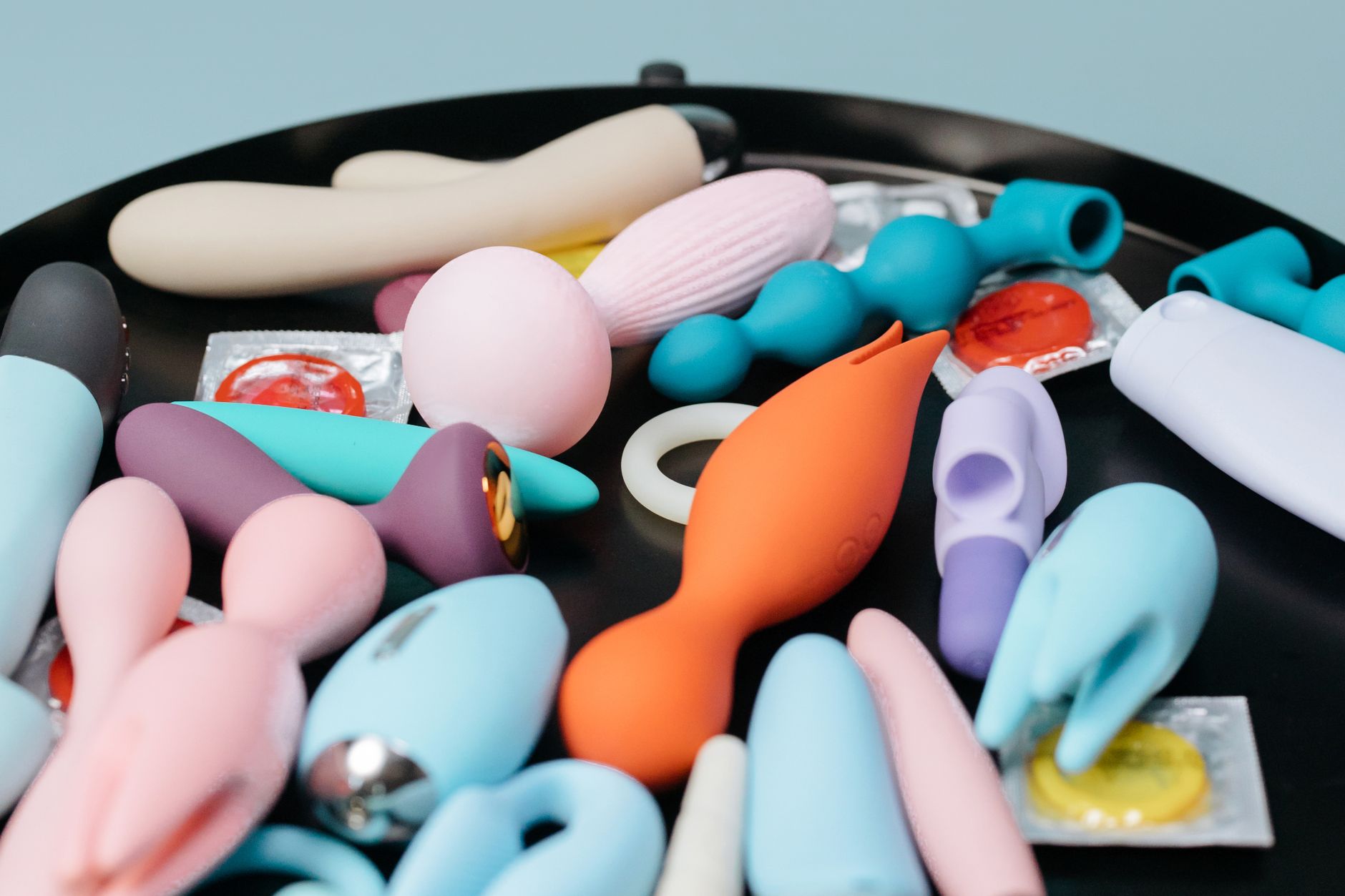 A collection of colorful vibrators on a black surface, representing tools for couples reconnection