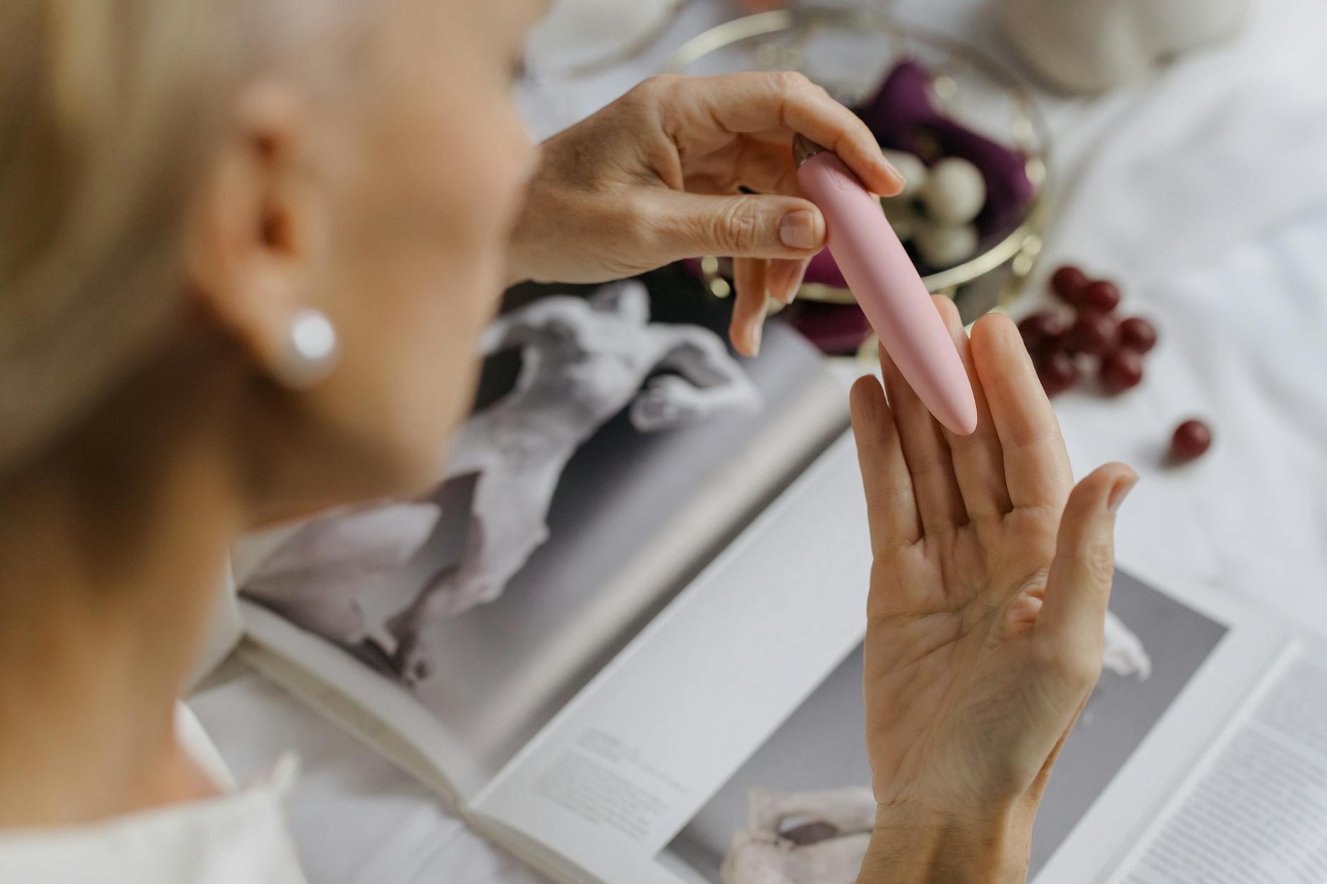 Woman holding a pink vibrator with personal items nearby, emphasizing intimate reconnection.