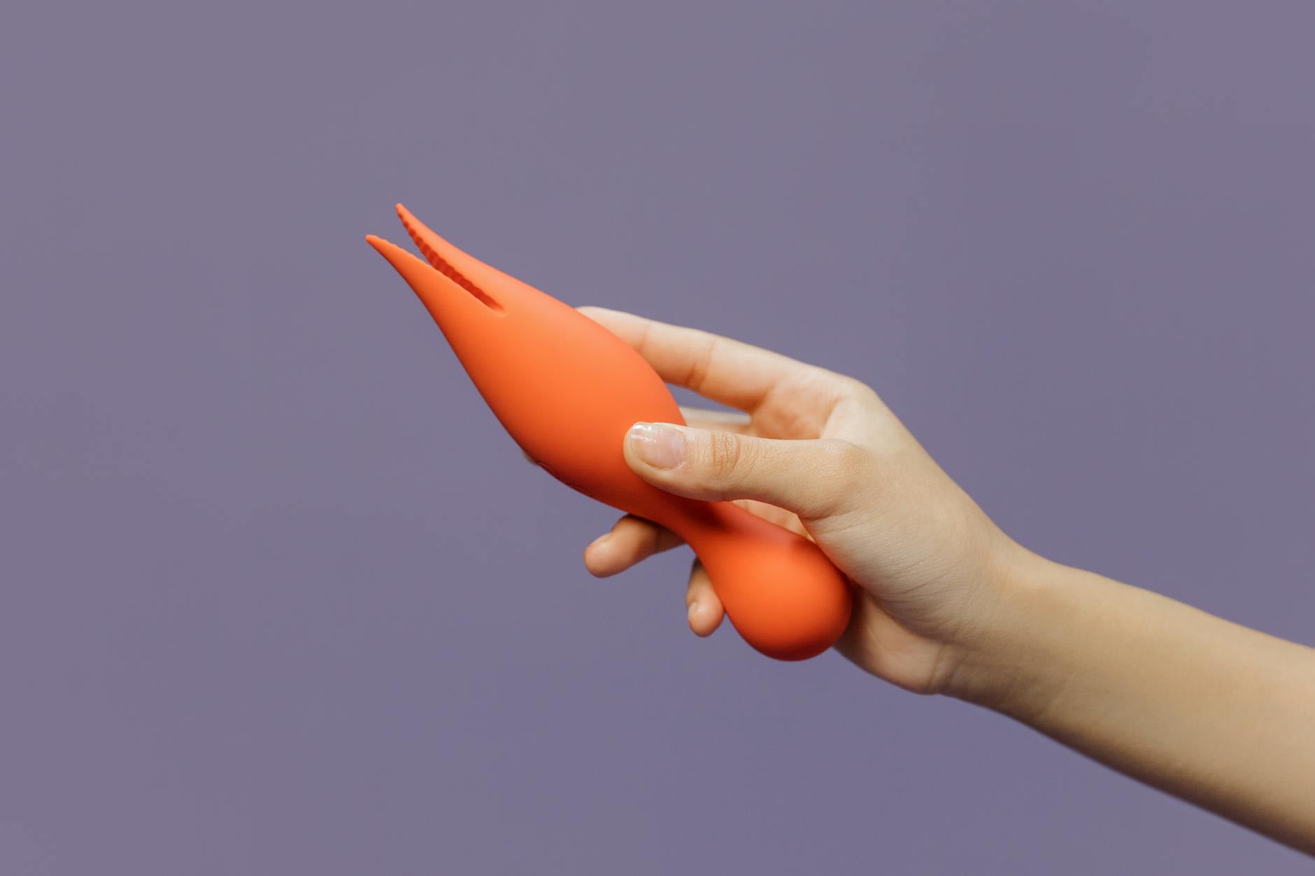 Hand holding a lemon vibrator against a minimalistic purple backdrop, conveying modern self-care and sensuality.