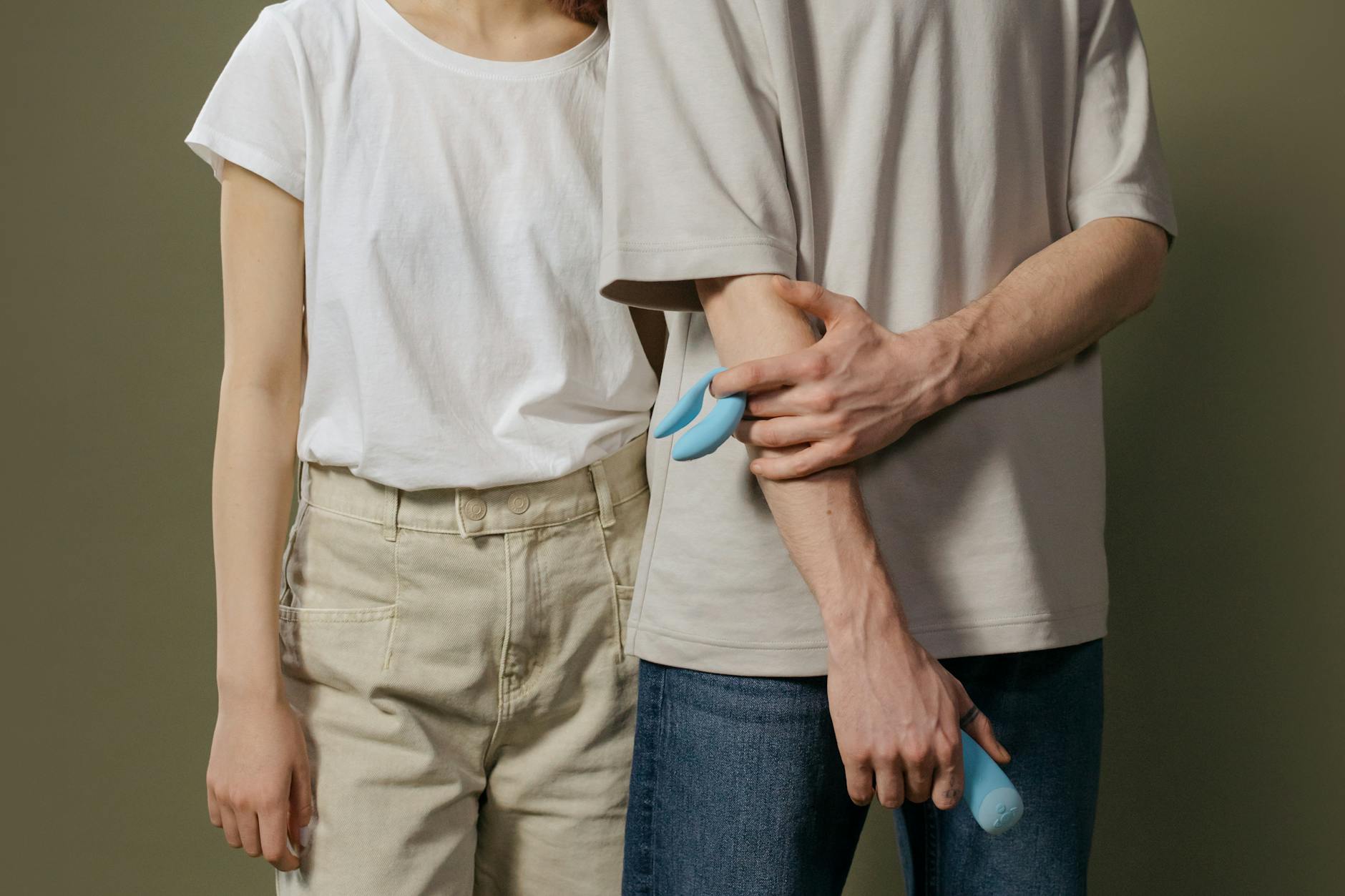A young couple standing together indoors, holding intimacy products, symbolizing modern connection.