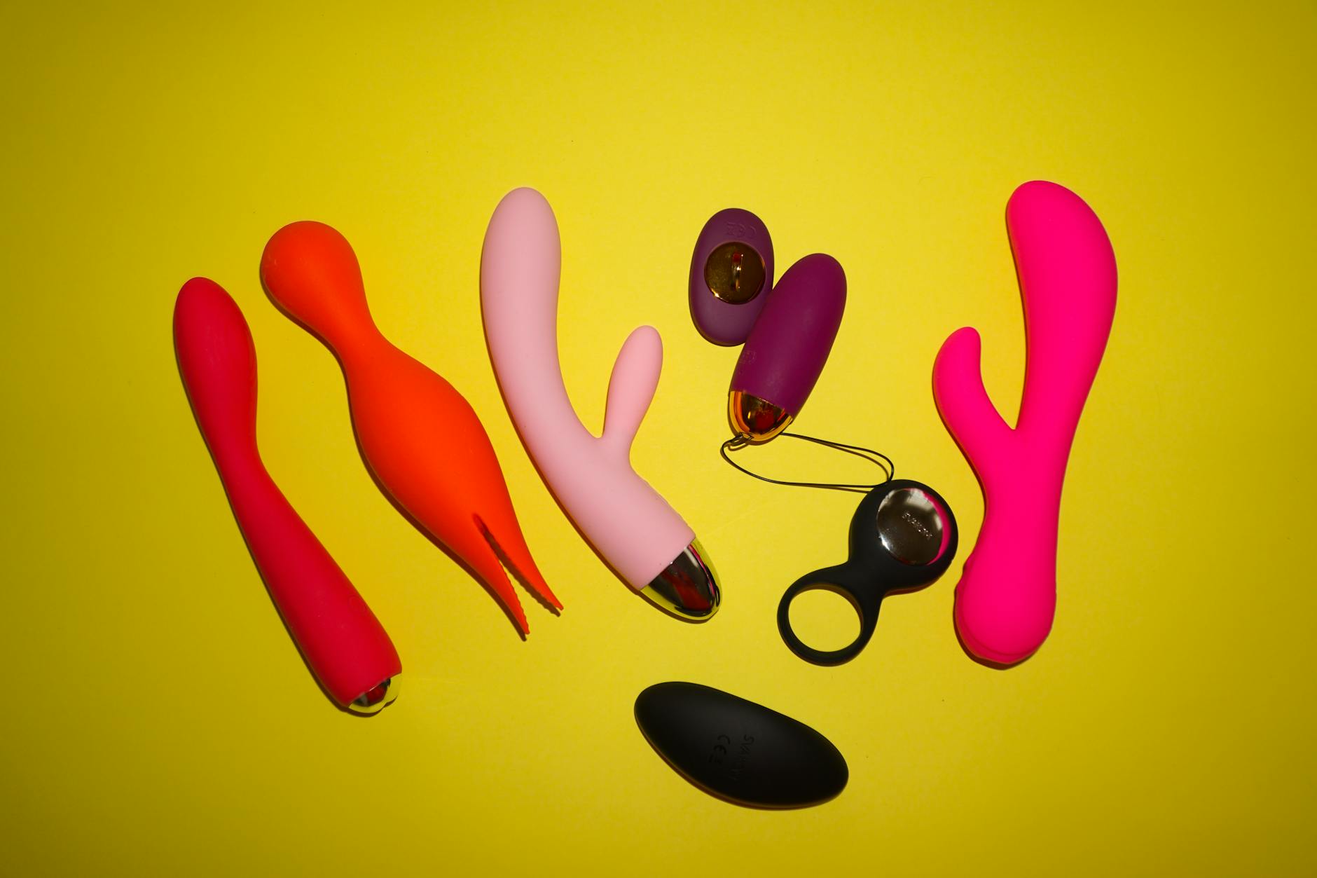 Hand holding a blue clitoral vibrator against a purple background, symbolizing self-care and reclaiming pleasure after relationship breach